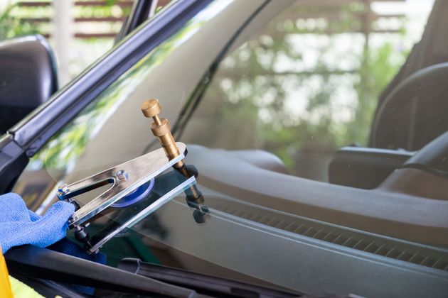 Windshield repair tool applying resin to a cracked car windshield