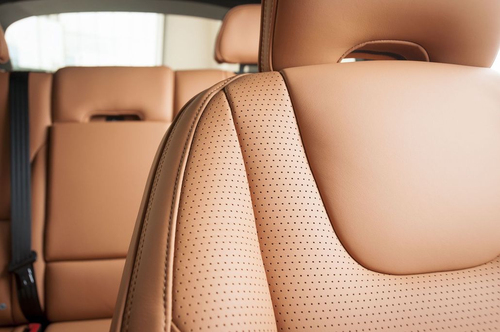 Close-up of a black leather car seat with visible stitching and blurred interior background