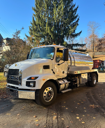 White dump truck parked outdoors on a residential street with trees in the background