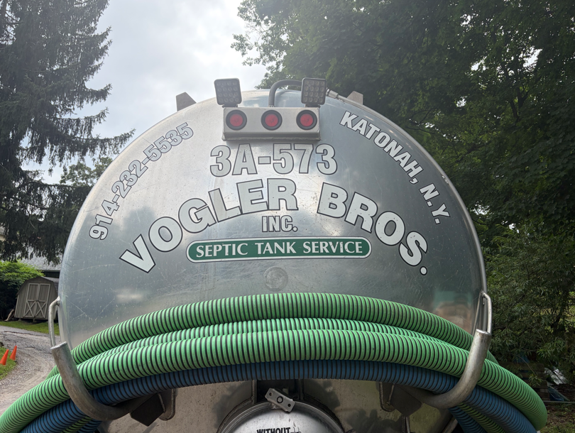 Rear of vacuum truck with “VOCLER BROS. INC.” and “Septic Tank Service” painted on tank