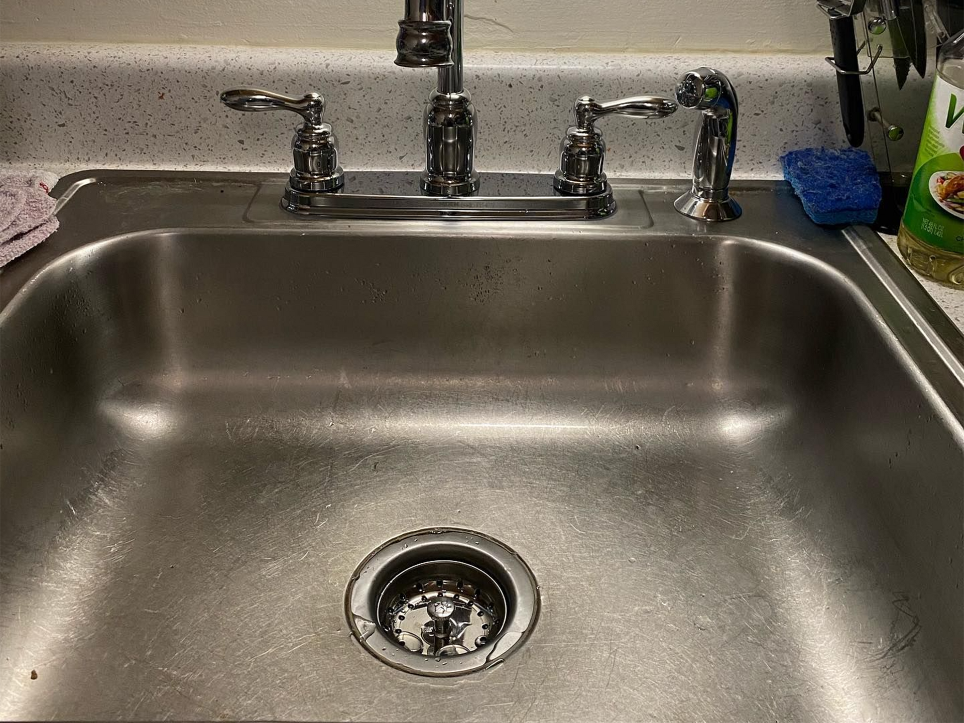 Stainless steel kitchen sink with faucet and drain.
