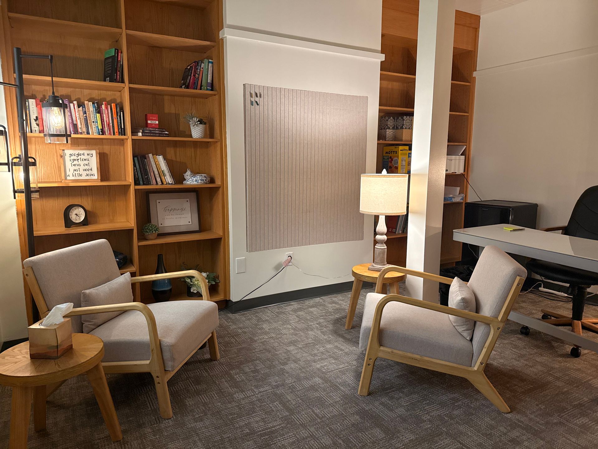 Cozy living room with two armchairs, a lamp, bookshelf, radiator, and a piano in the background