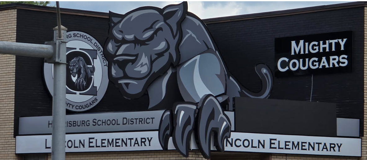 A school sign with a cougar mascot, Mighty Cougars text, and Lincoln Elementary name.