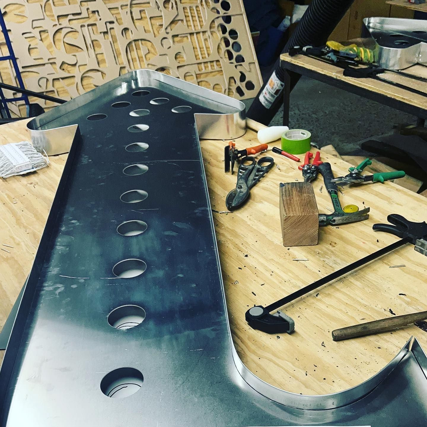 A wooden table with a piece of metal and tools on it