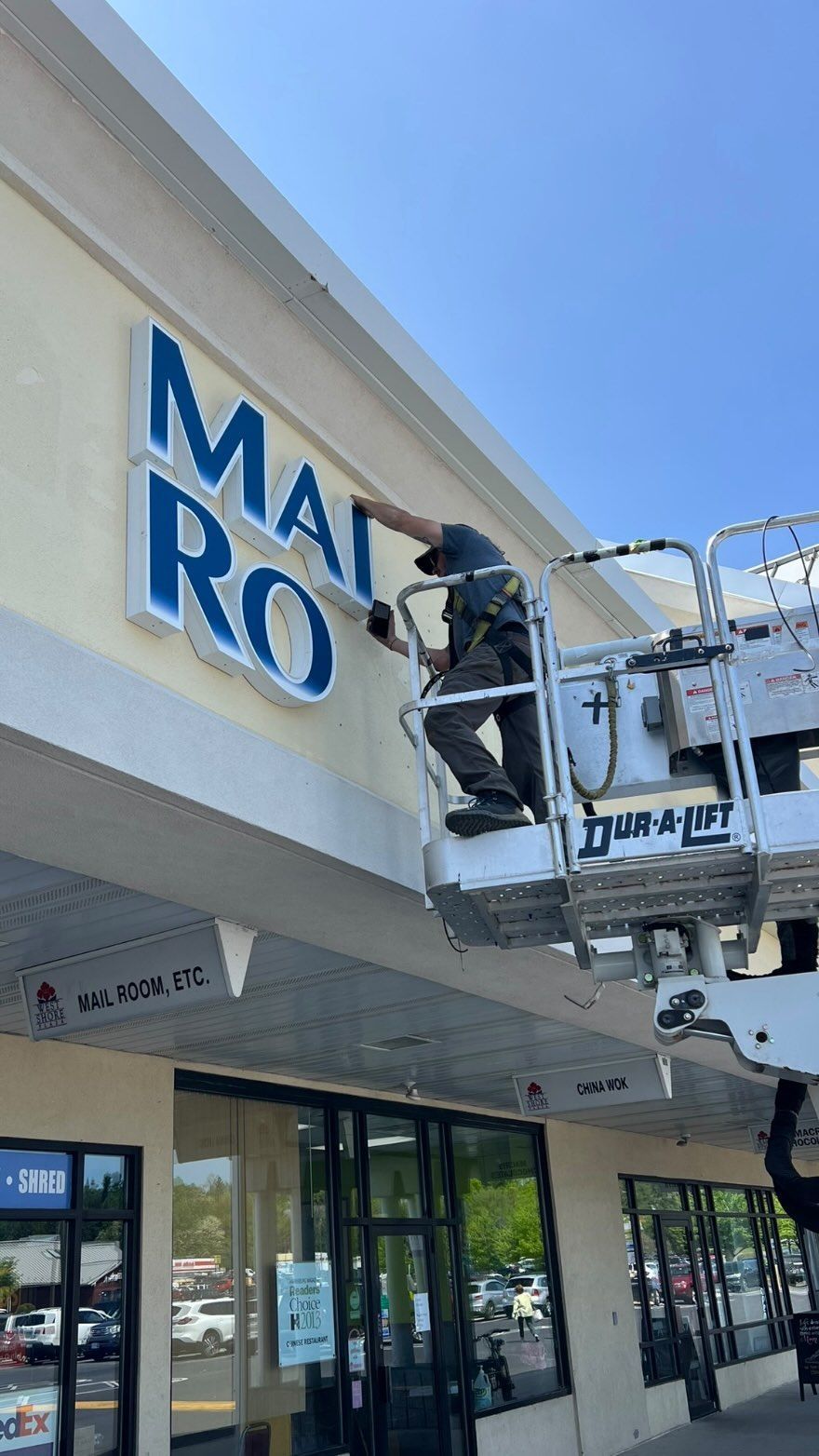 A man is installing a sign on the side of a building.