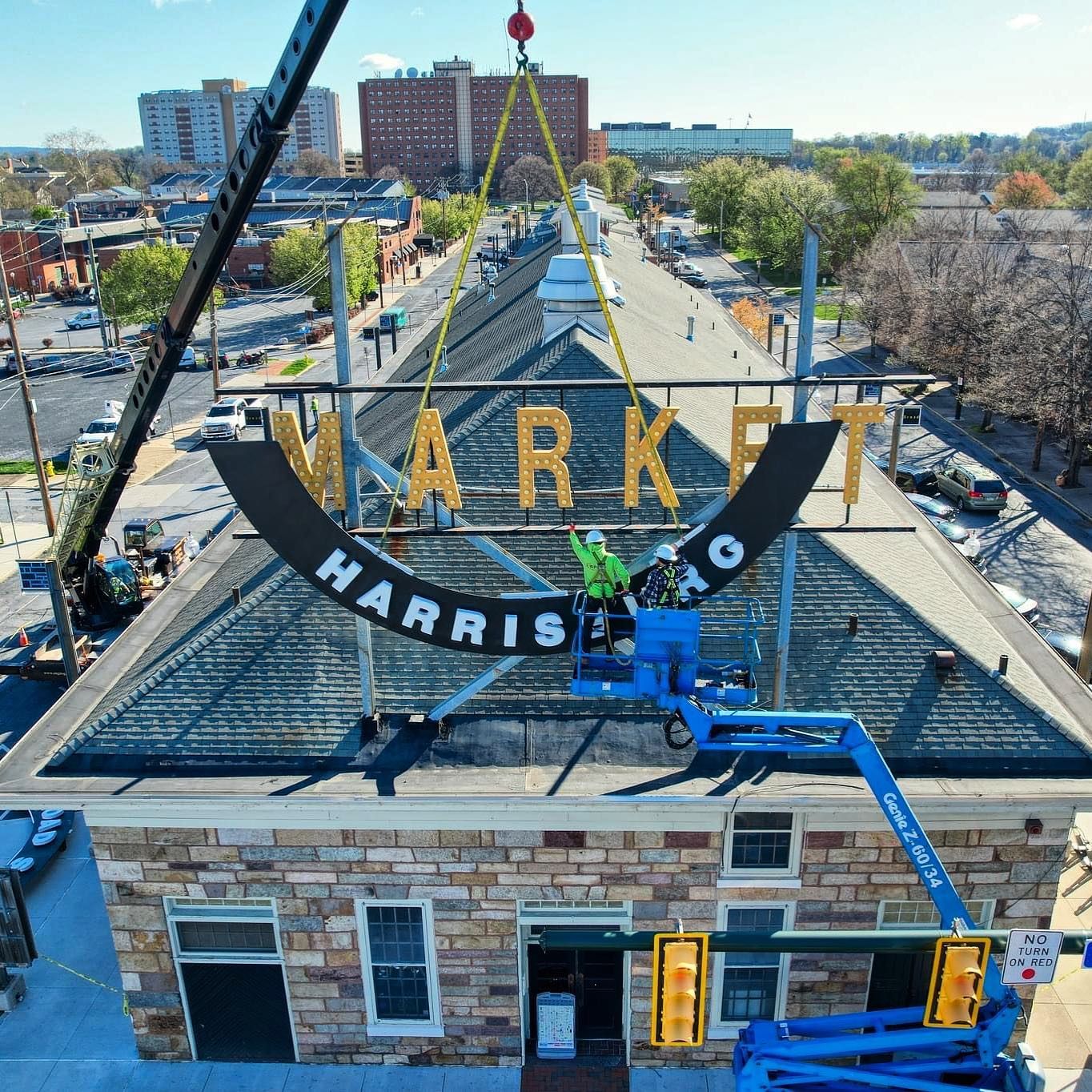 A crane is lifting a sign on top of a building that says harrisburg