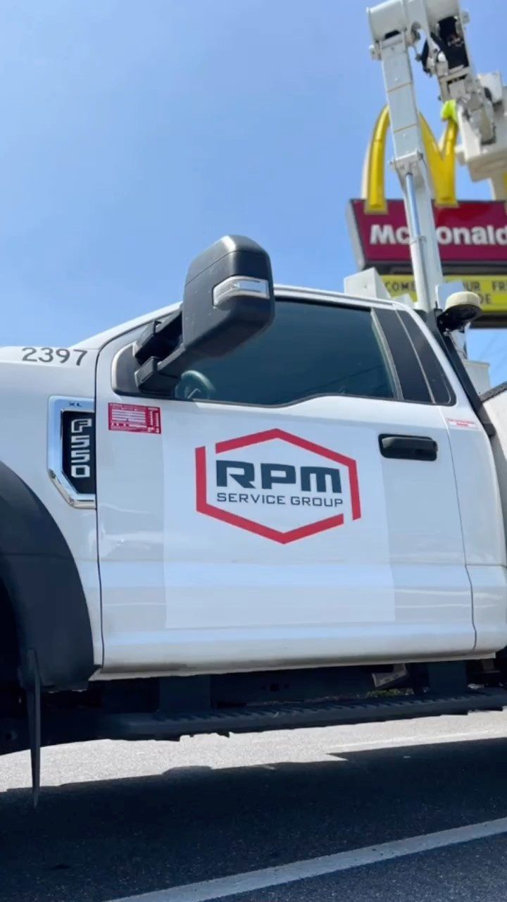 A white truck is parked in front of a mcdonald 's sign.