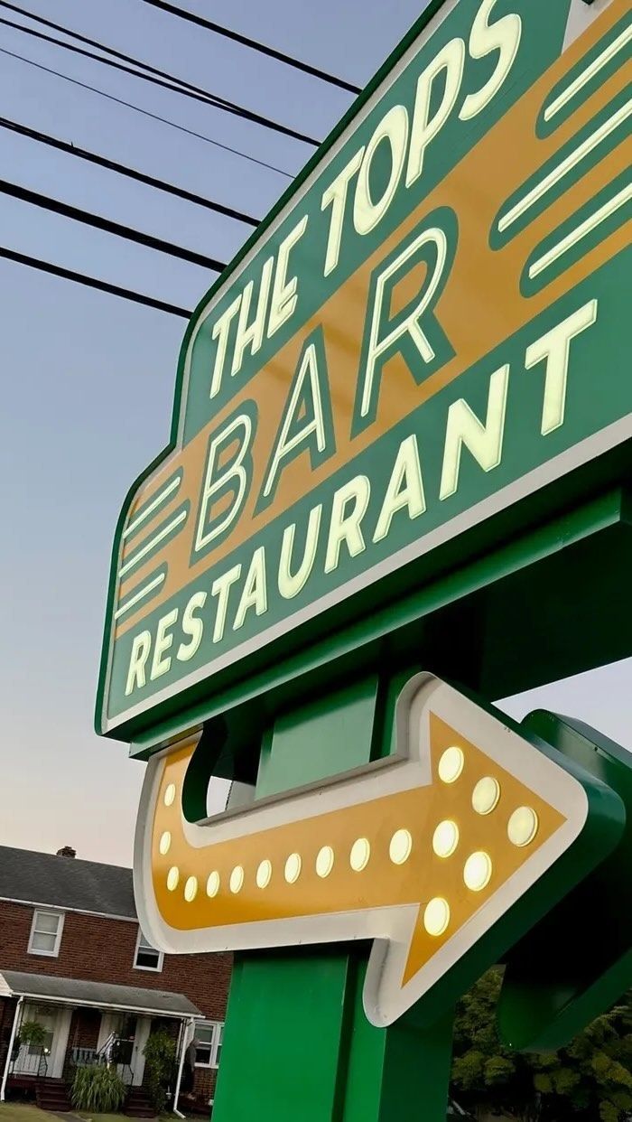 A green and yellow sign for the tops bar restaurant