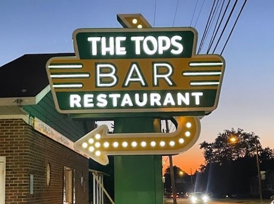 A green and yellow sign for the tops bar restaurant