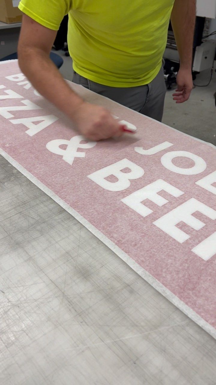 A man in a yellow shirt is working on a sign that says pizza & joe beef