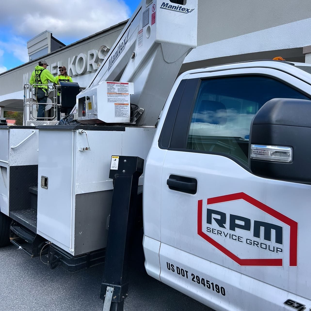 A white rpm service group truck is parked in front of a building.