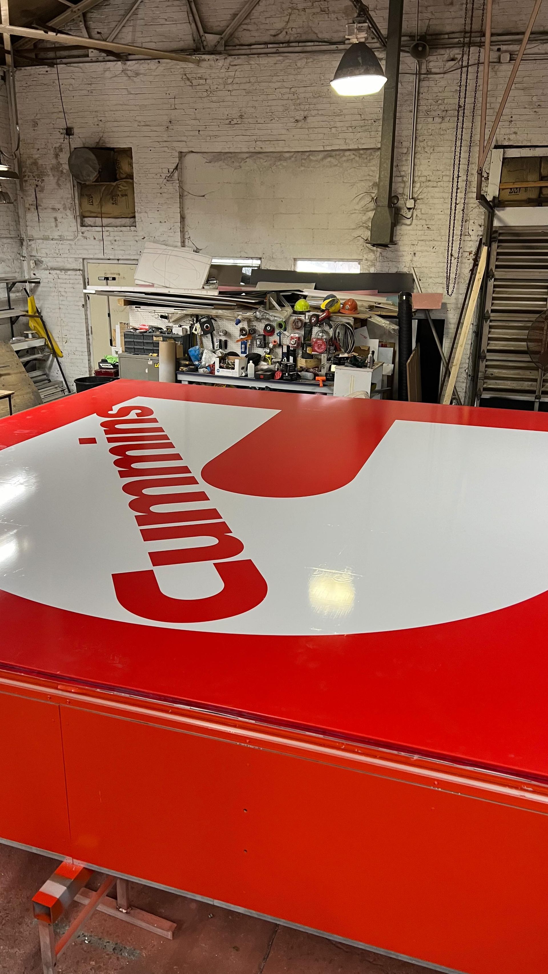 A red and white sign with the word cummins on it is in a garage.