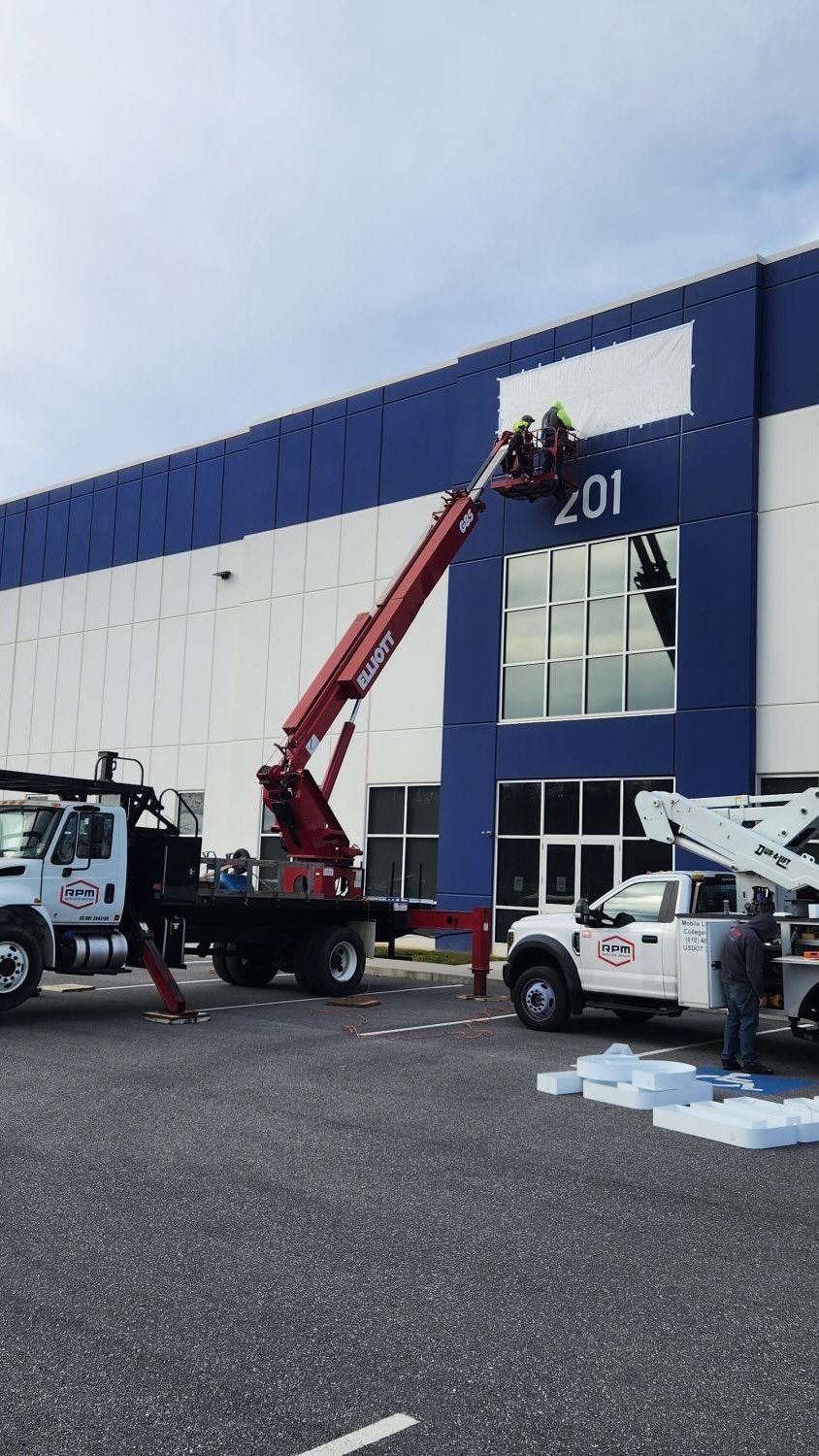 A crane is being used to install a sign on the side of a building.