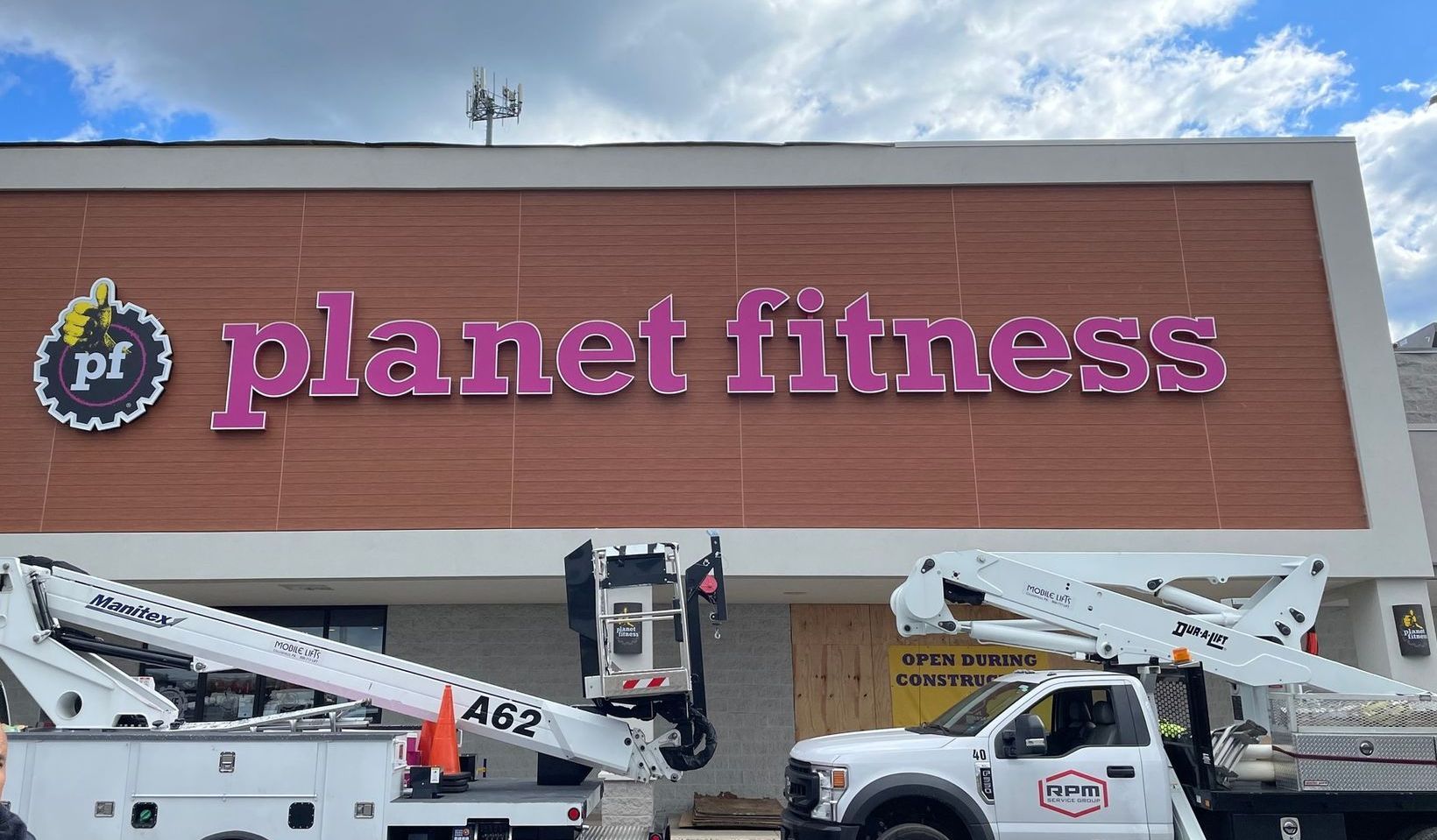 A white truck is parked in front of a planet fitness building.
