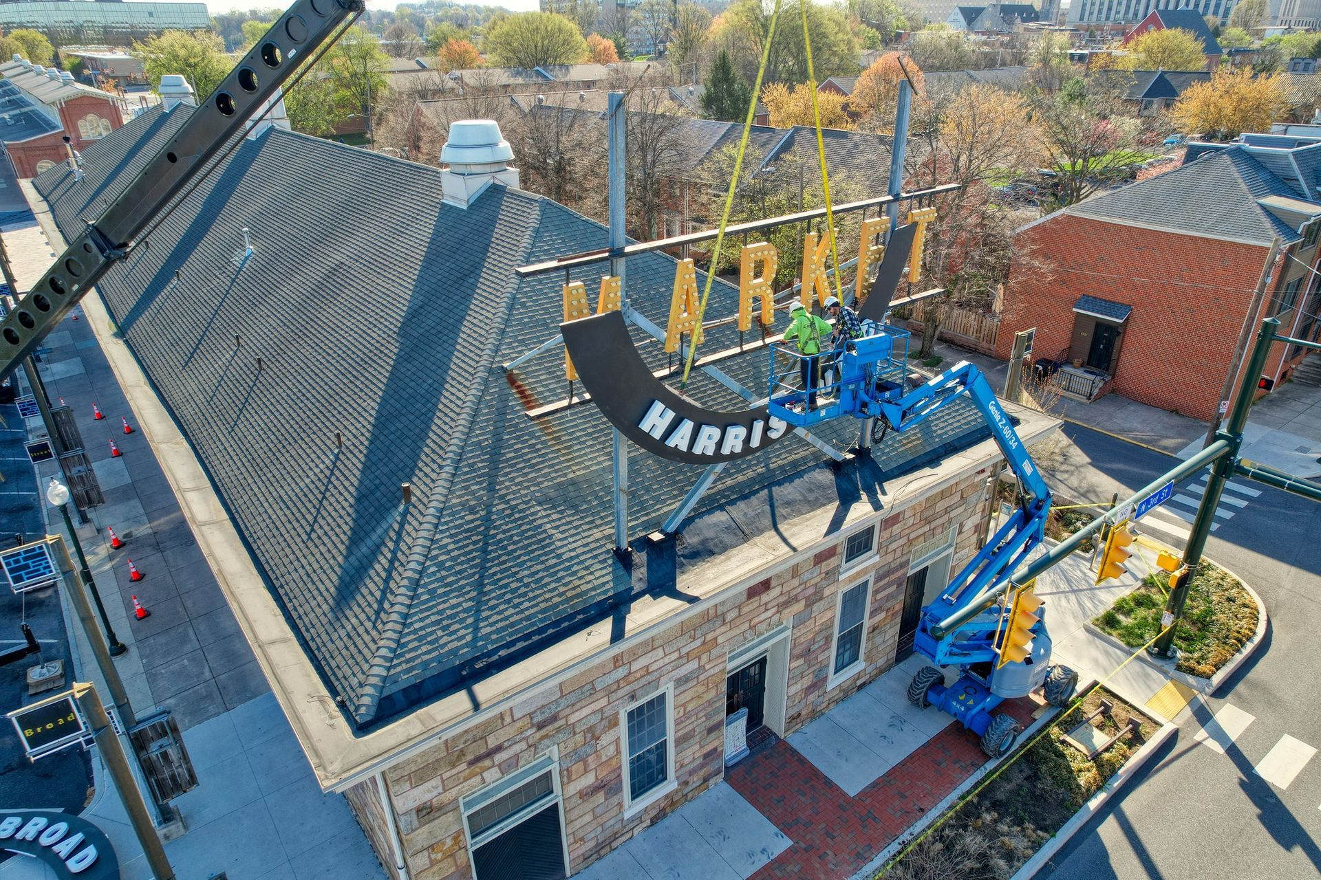 An aerial view of a sign being installed on the roof of a building.
