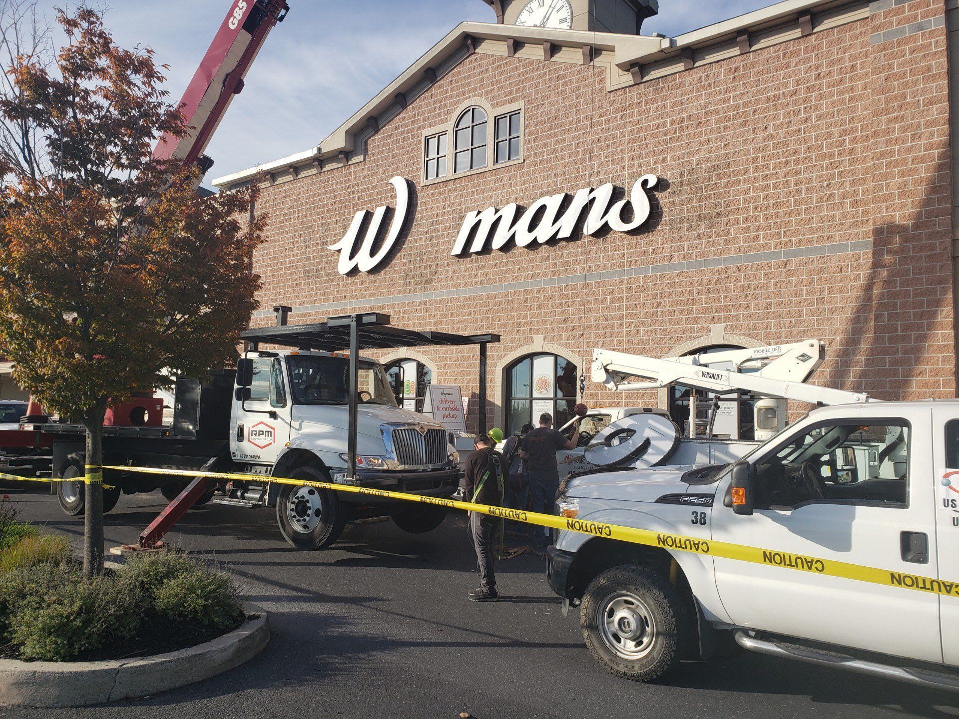 A team is installing a sign on the side of a building.
