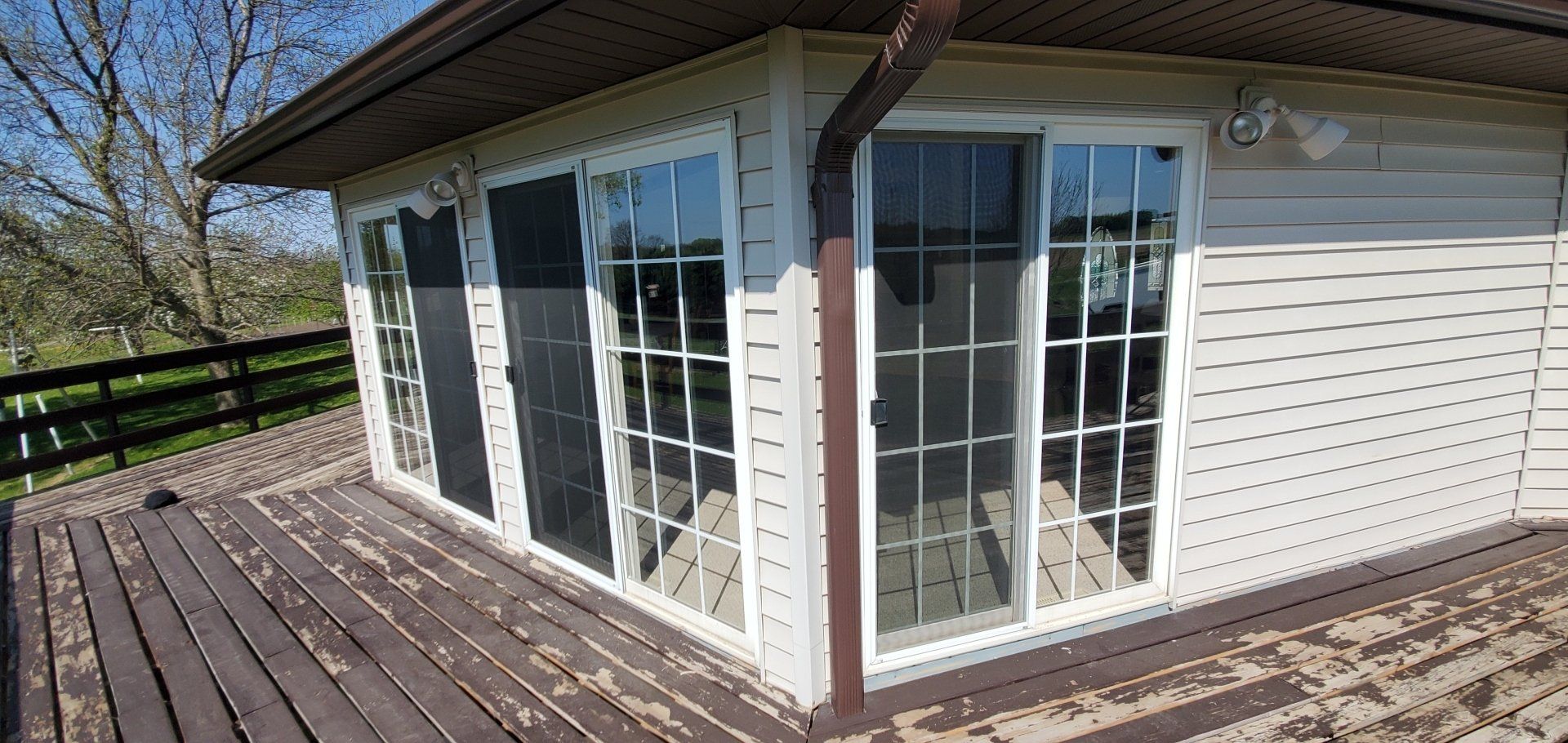 A white house with sliding glass doors and a wooden deck