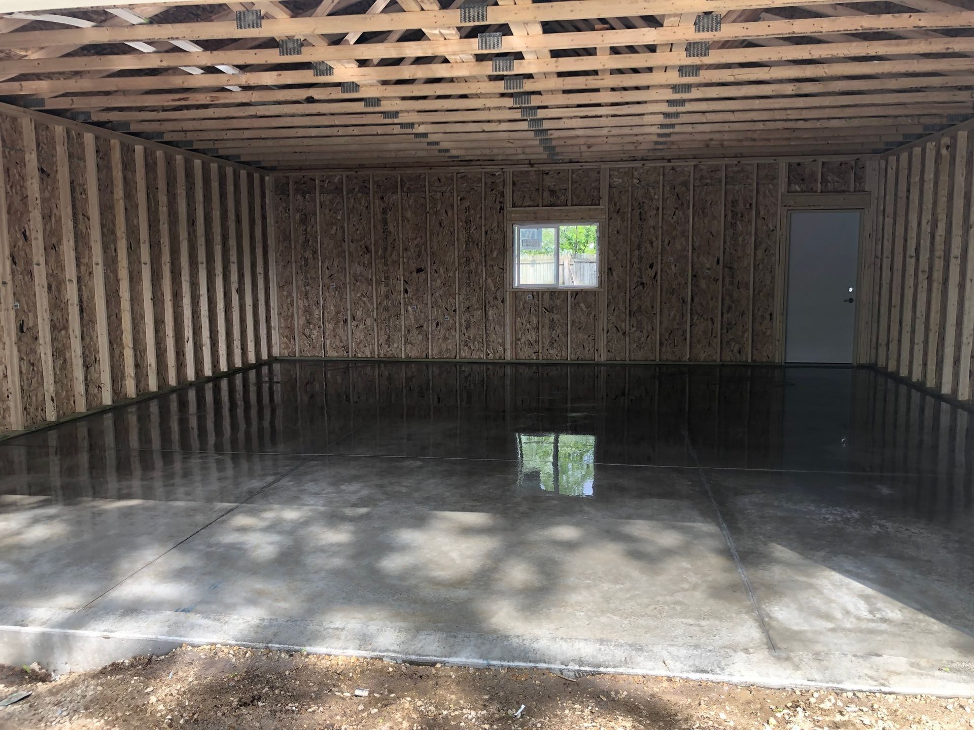 An empty garage with a concrete floor and wooden walls.