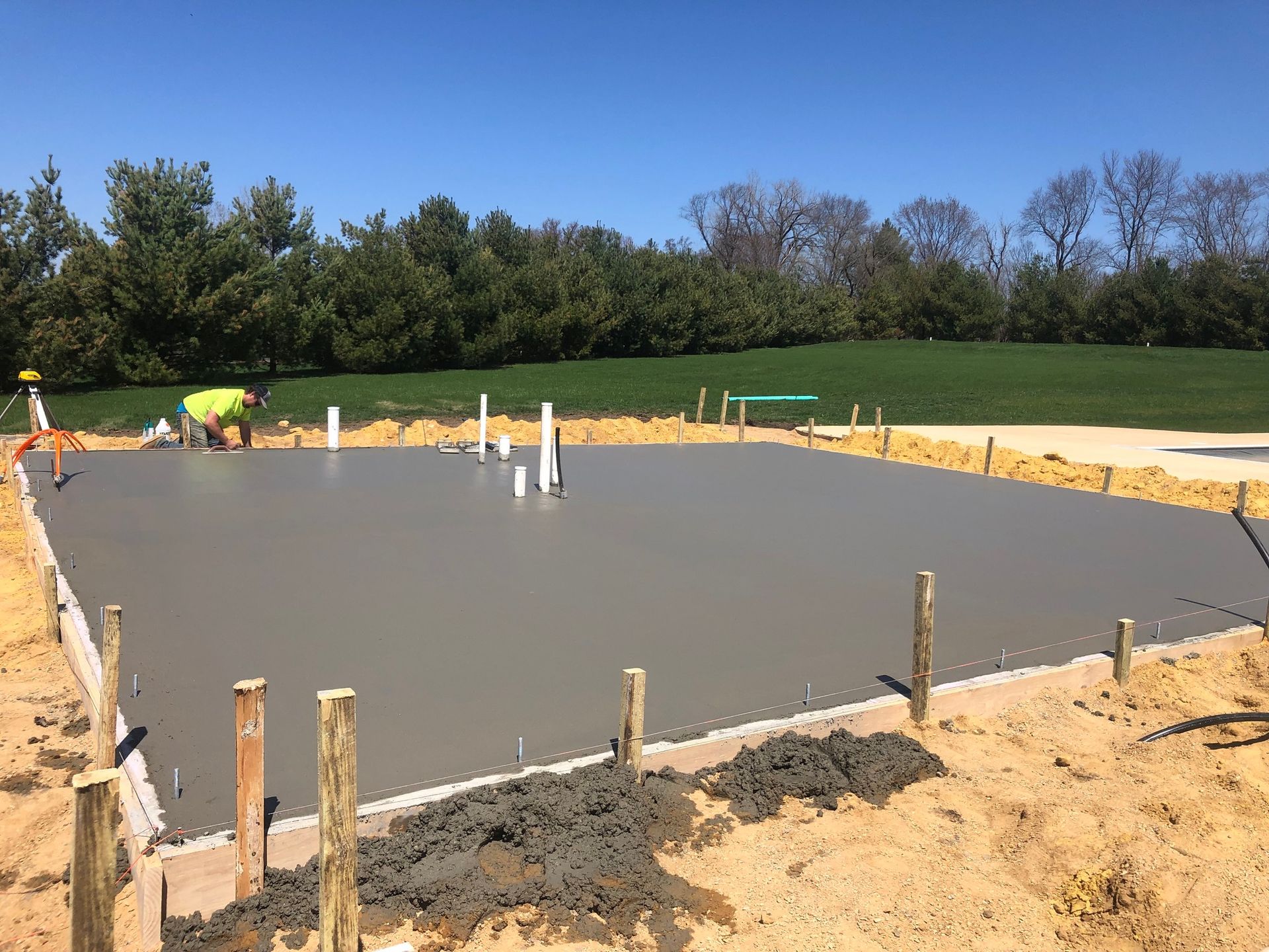 A man is working on a concrete foundation for a house.