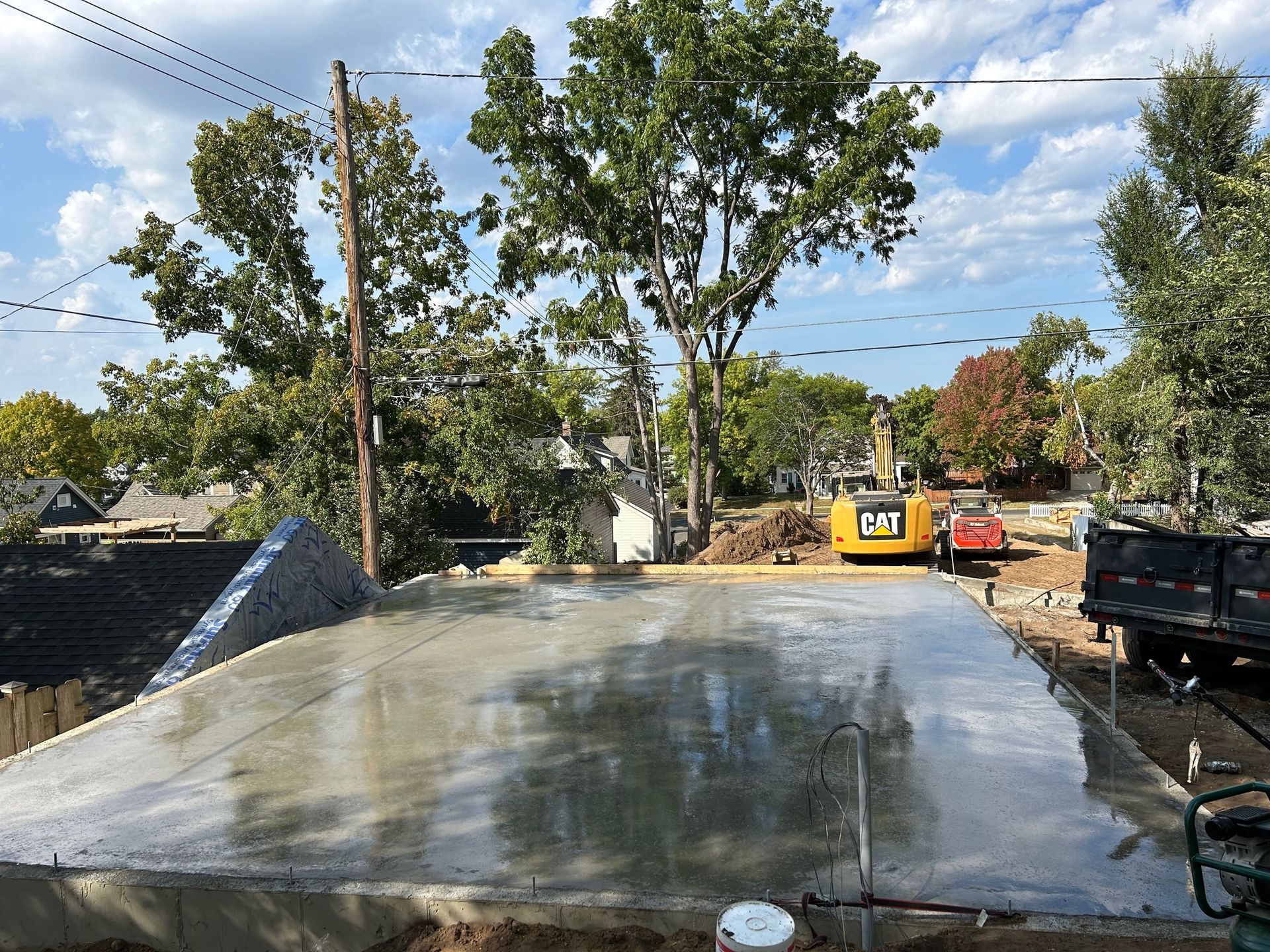 A large concrete slab is being built with a cat excavator in the background.