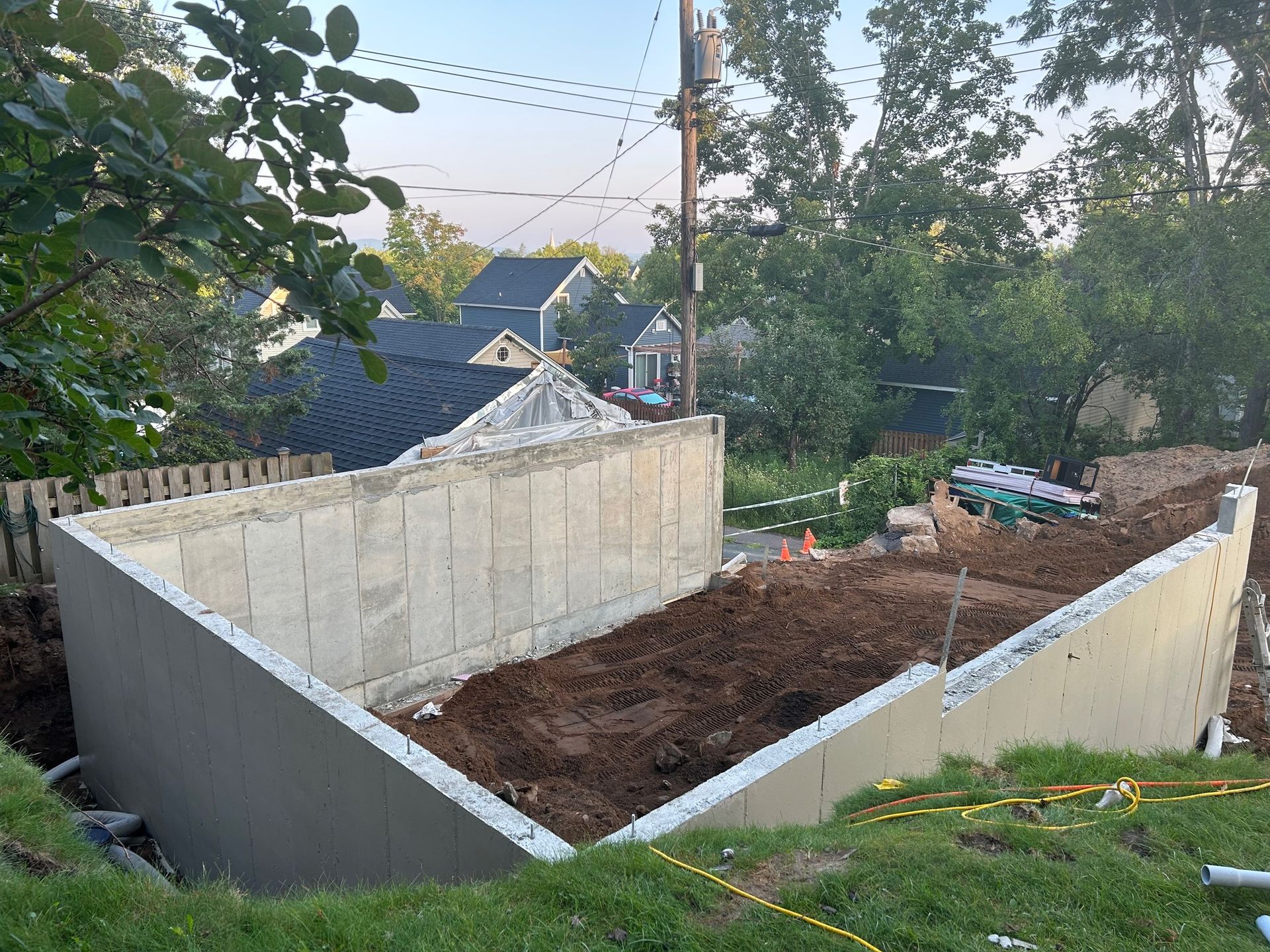 A large concrete wall is being built in the backyard of a house.