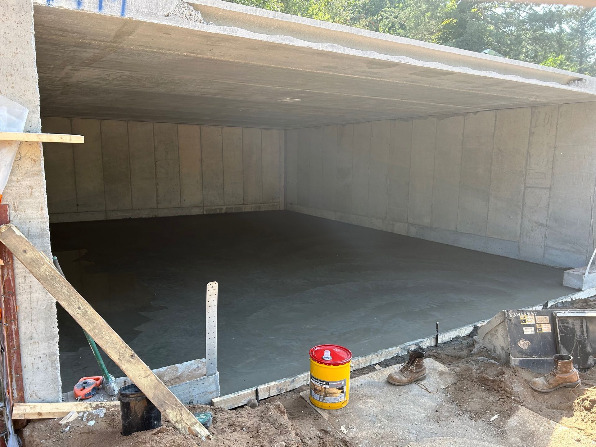 A concrete floor is being poured in a garage under construction.