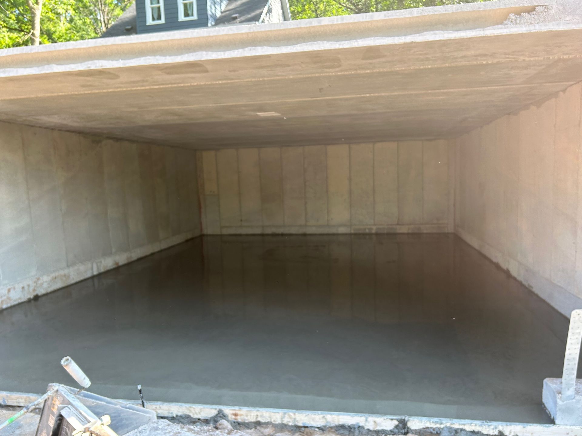 A concrete floor is being poured in a garage under construction.