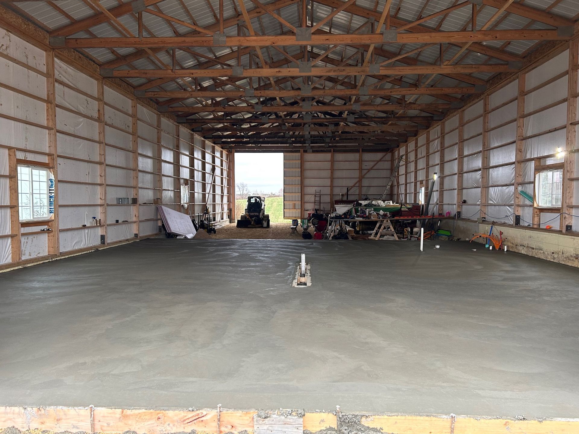 A large warehouse with a concrete floor and a tractor in the background.