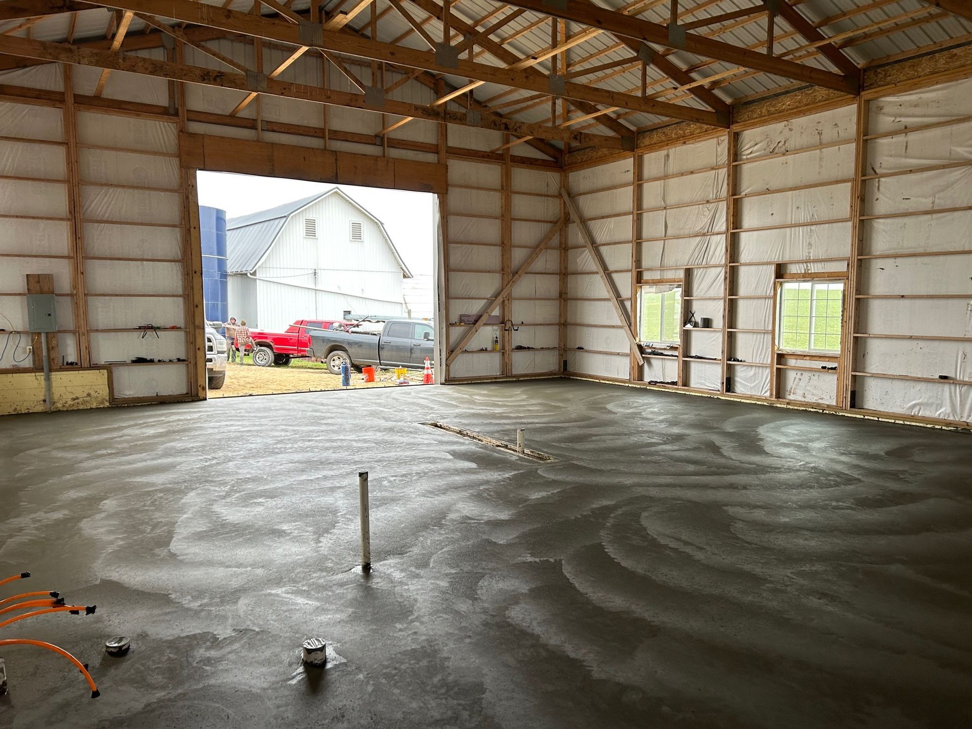 A large building with a concrete floor and a barn in the background.