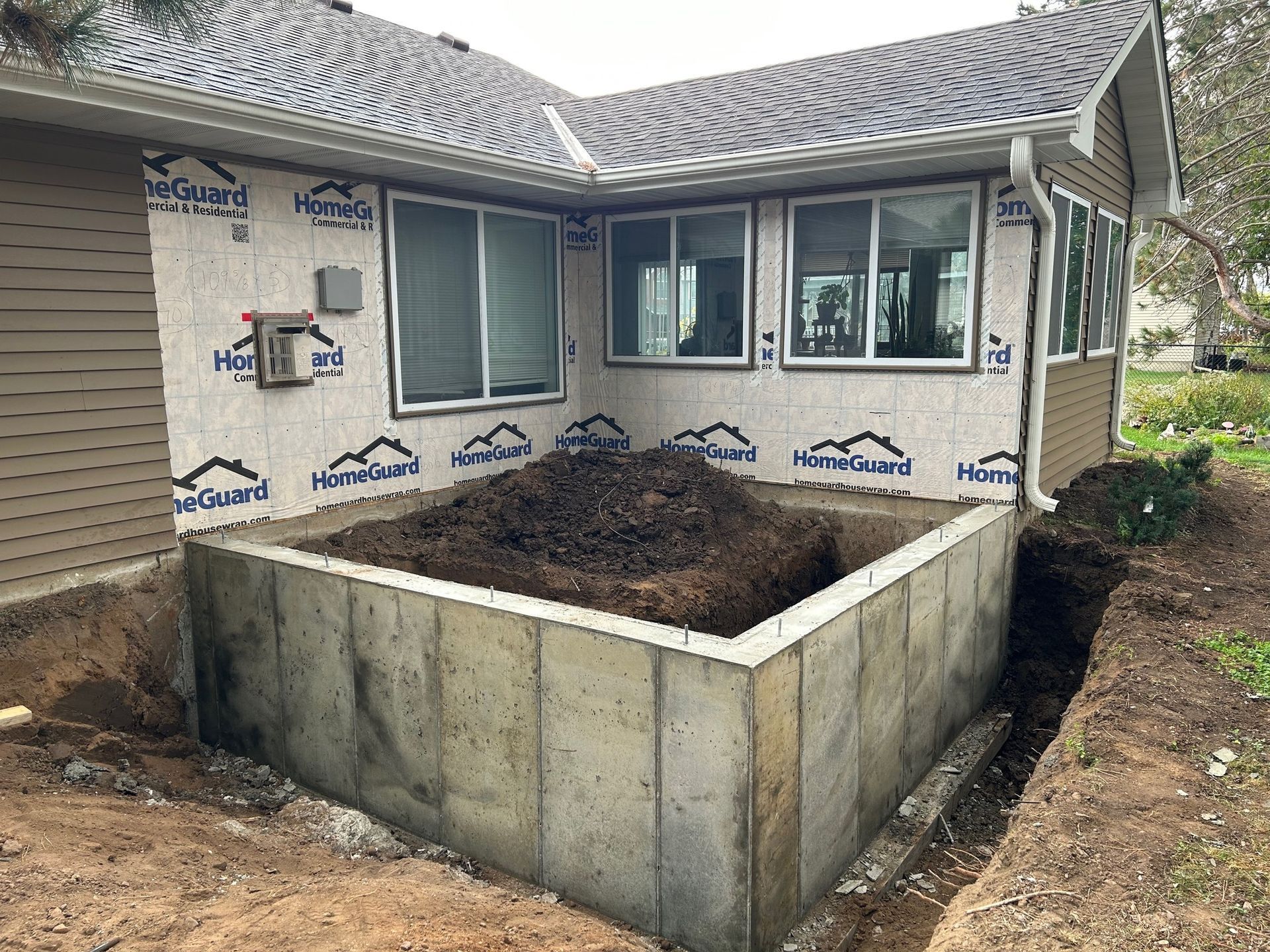 A concrete wall is being built in front of a house.
