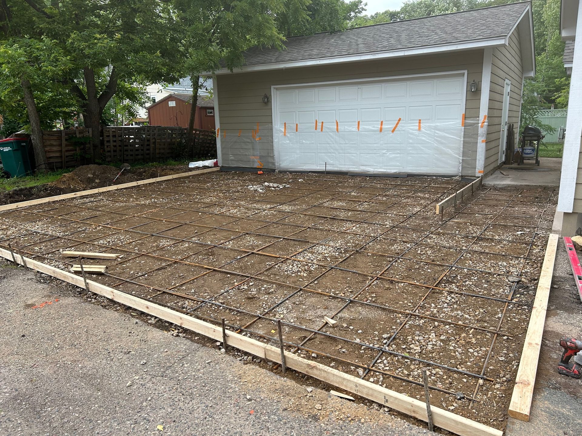 A concrete driveway is being built in front of a garage.