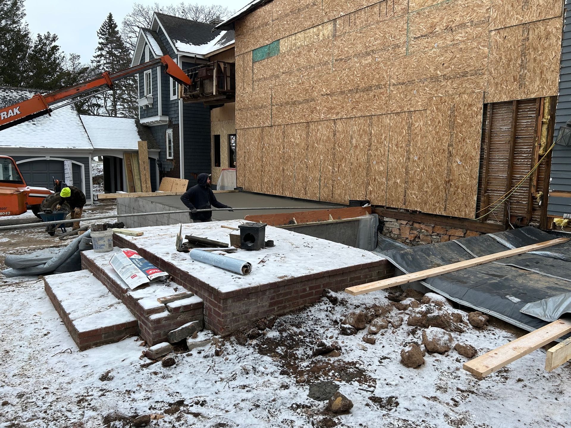 A house is being built in the snow with a crane in the background.