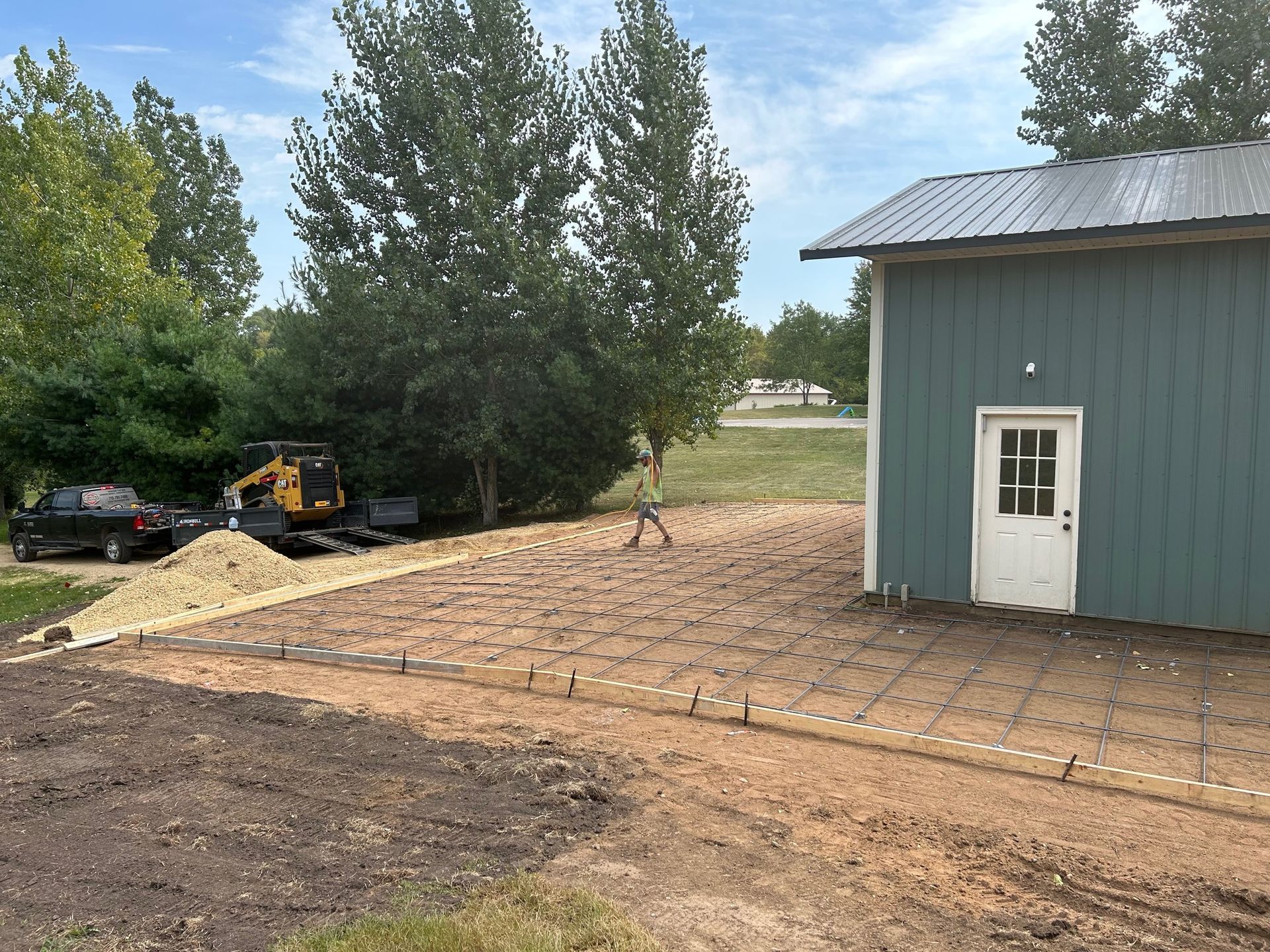 A green building with a white door is sitting in the middle of a dirt field.