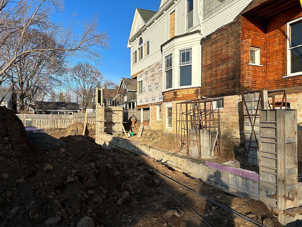 A large pile of dirt is in front of a building under construction.