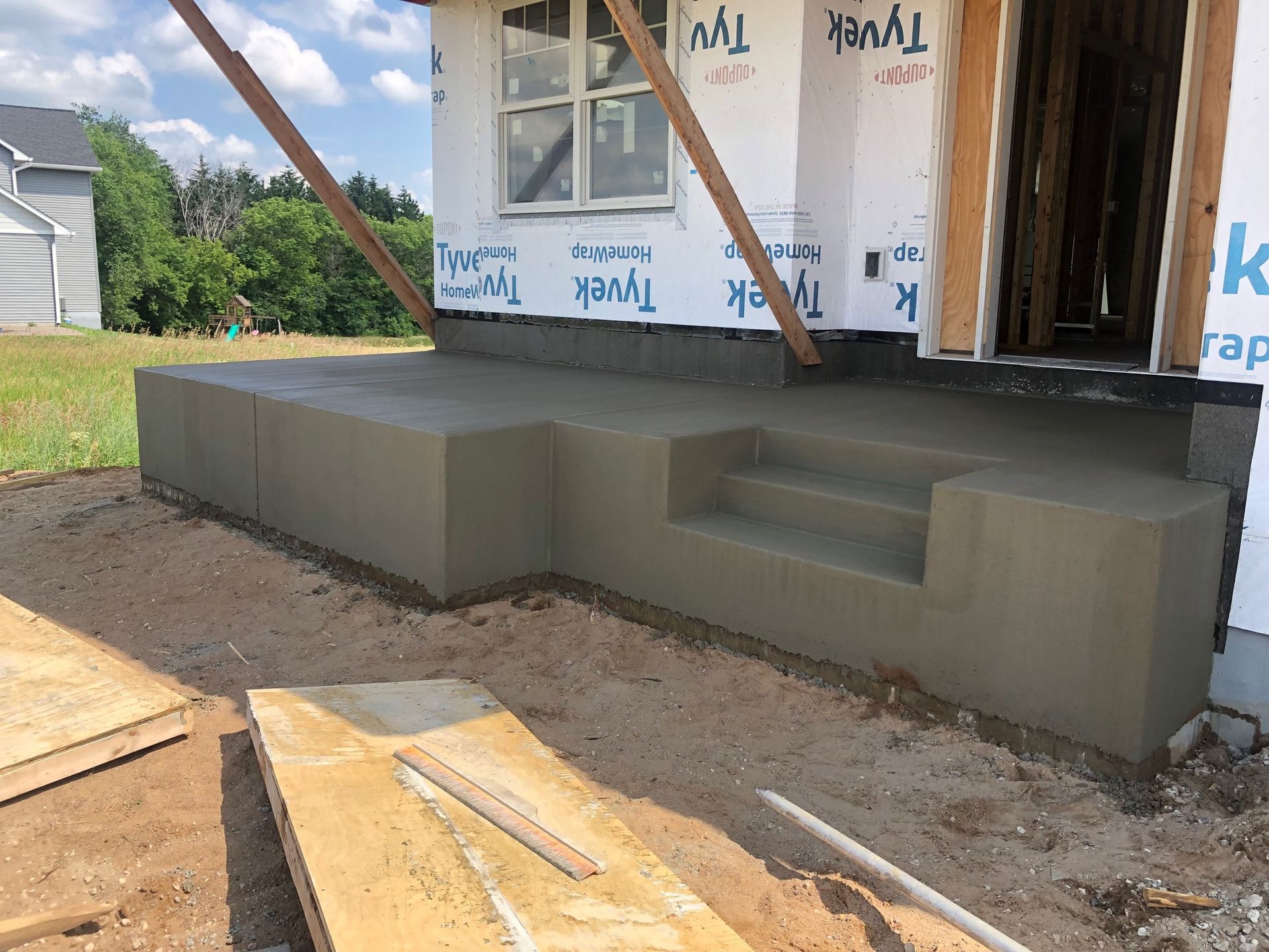 A concrete porch is being built in front of a house.