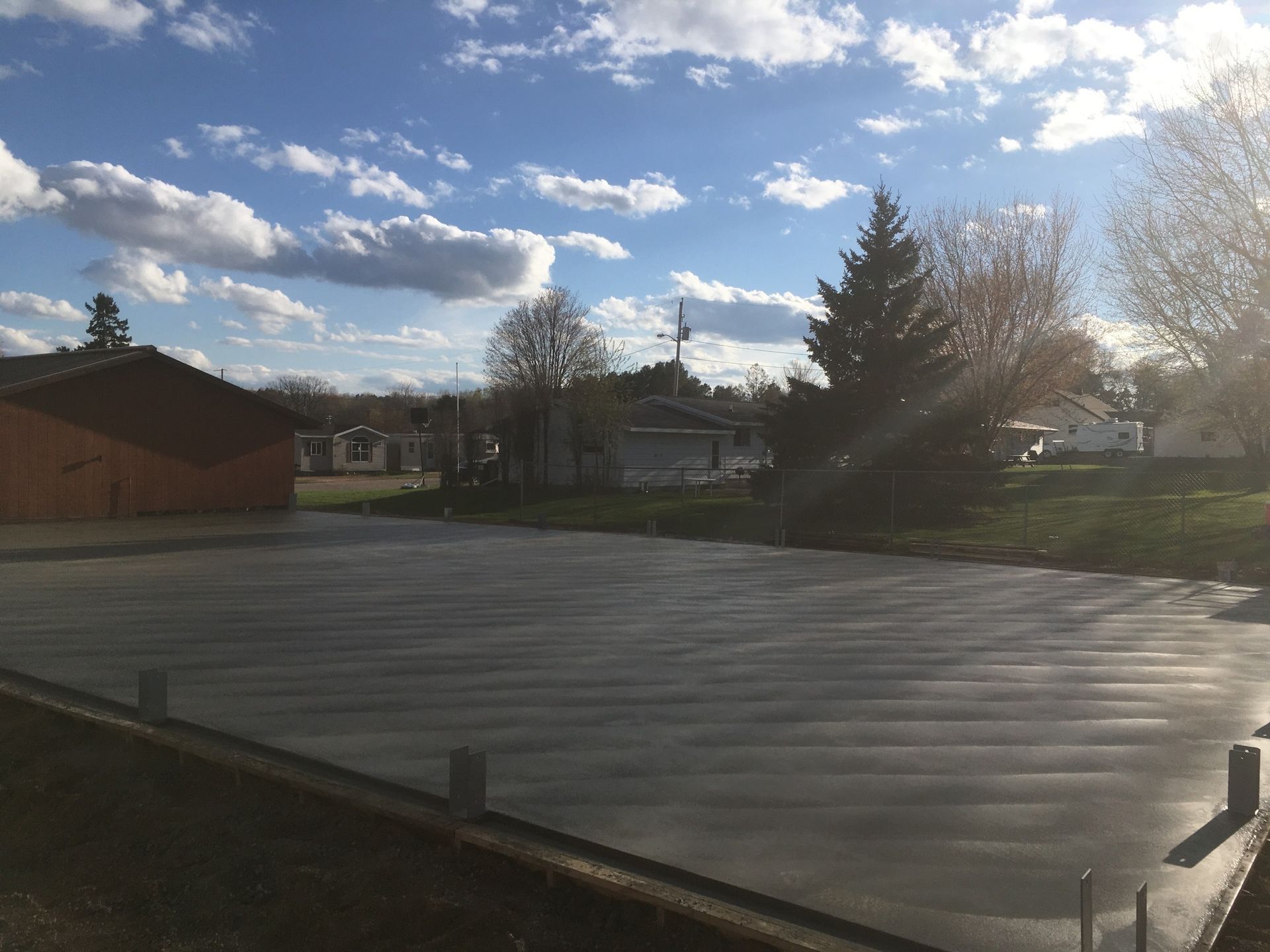 A concrete driveway with a blue sky and clouds in the background.