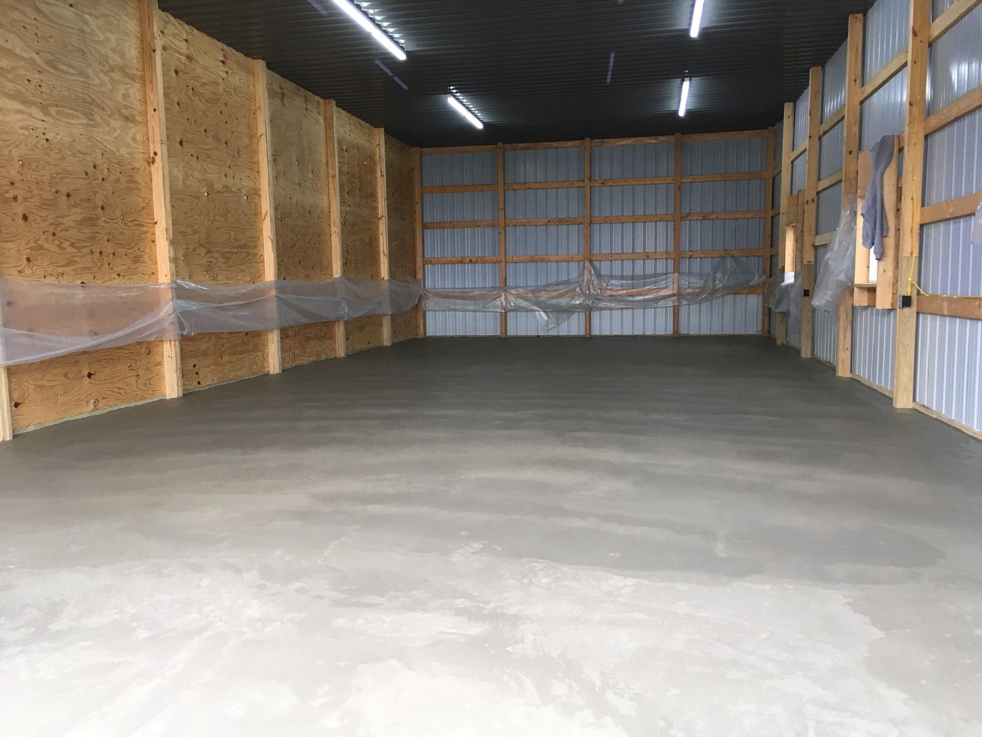 An empty garage with a concrete floor and wooden walls.