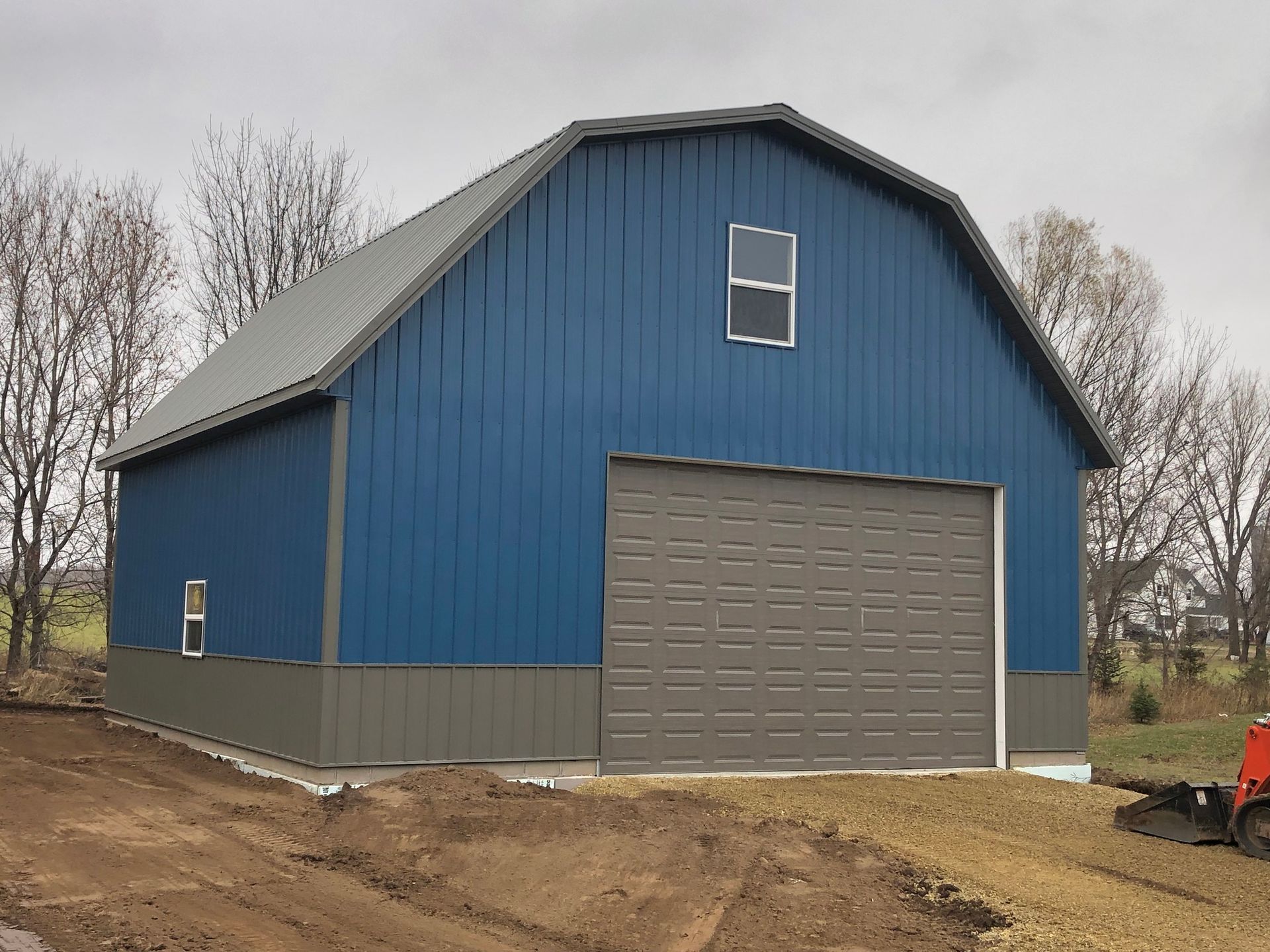A blue barn with a large garage door and a window.