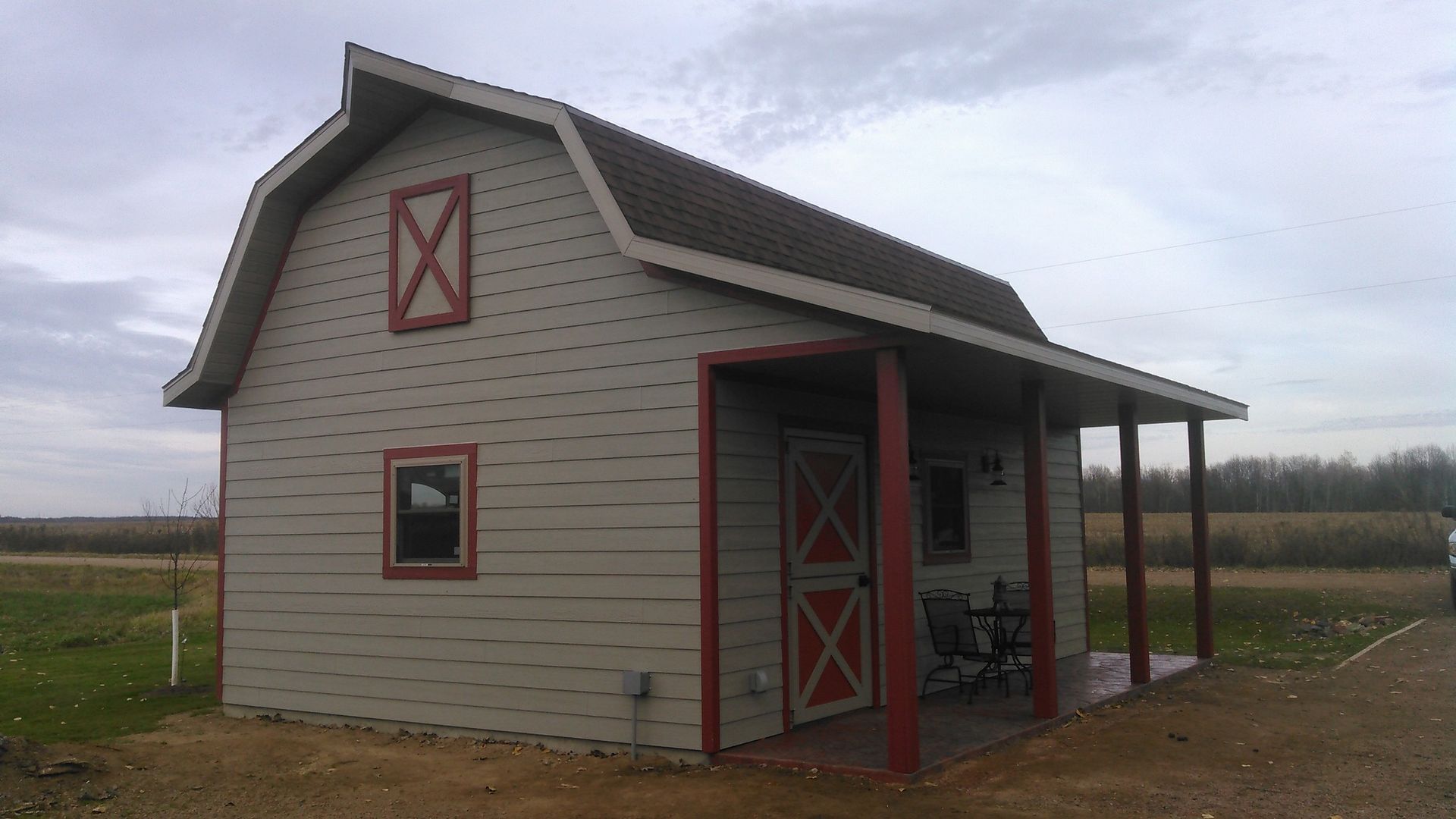 A small barn with a porch and a red door