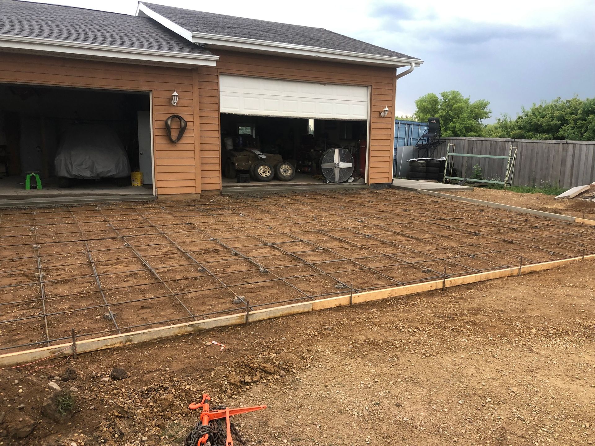 A house with a garage and a dirt driveway in front of it.