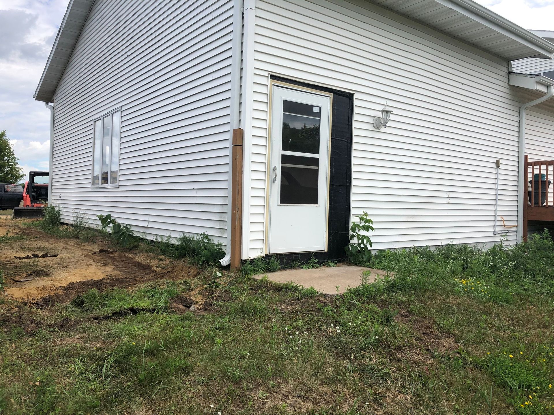 A white house with a black door is sitting in the middle of a grassy field.