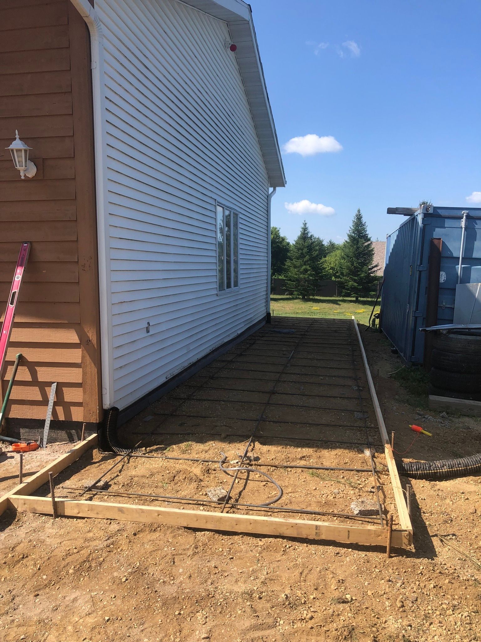 A house with a concrete driveway being built in front of it.