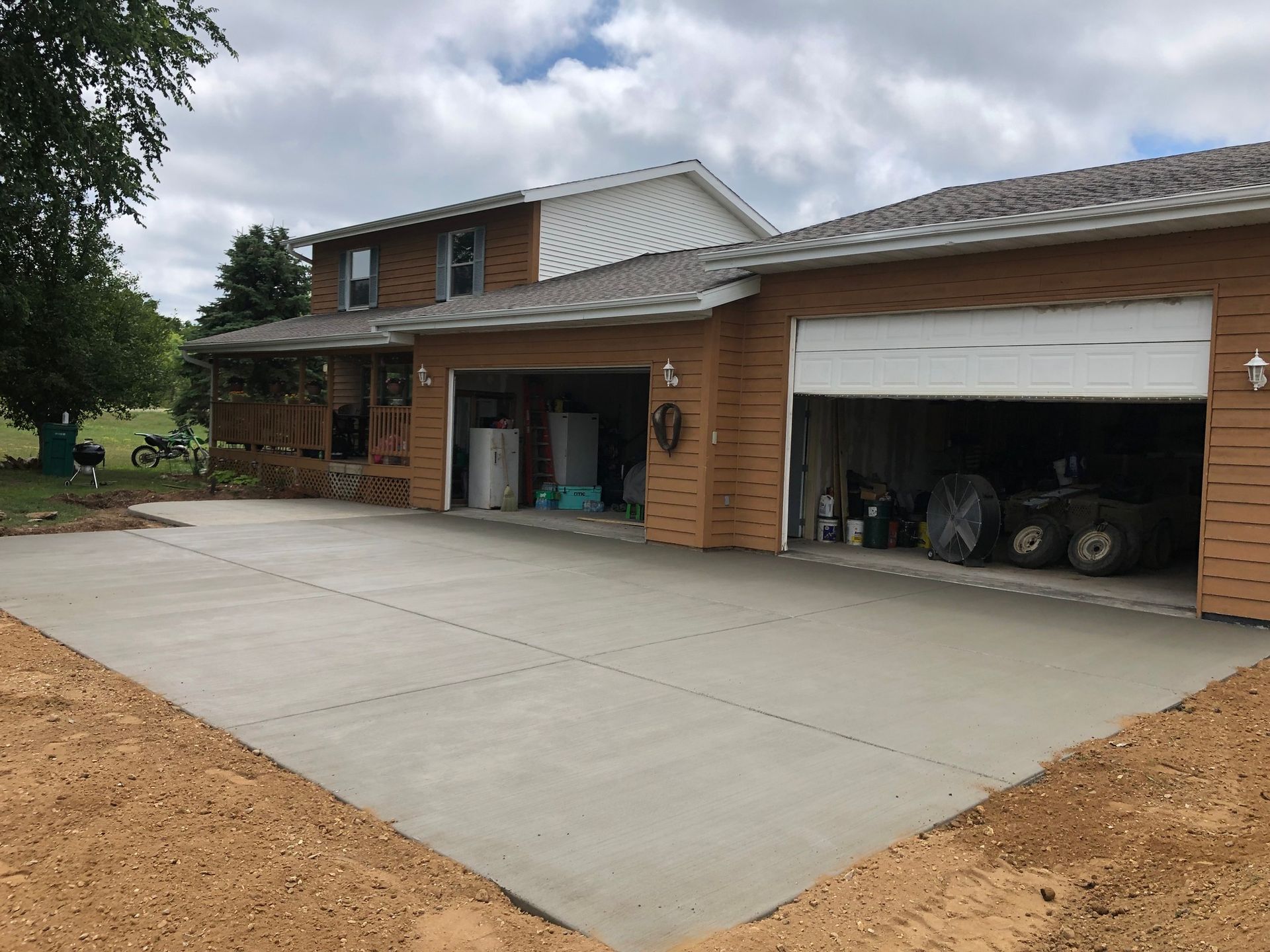 A house with two garages and a concrete driveway in front of it.