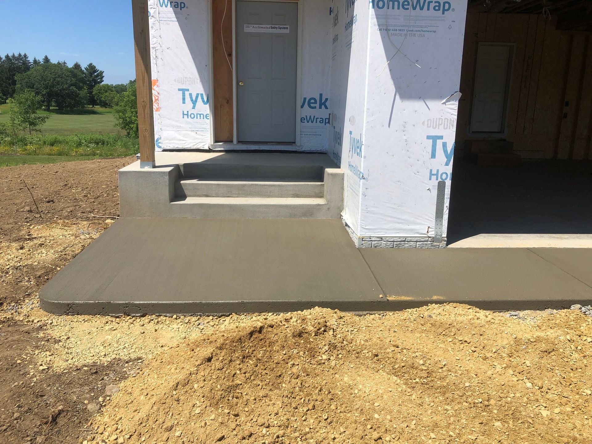 A concrete walkway is being built in front of a house under construction.