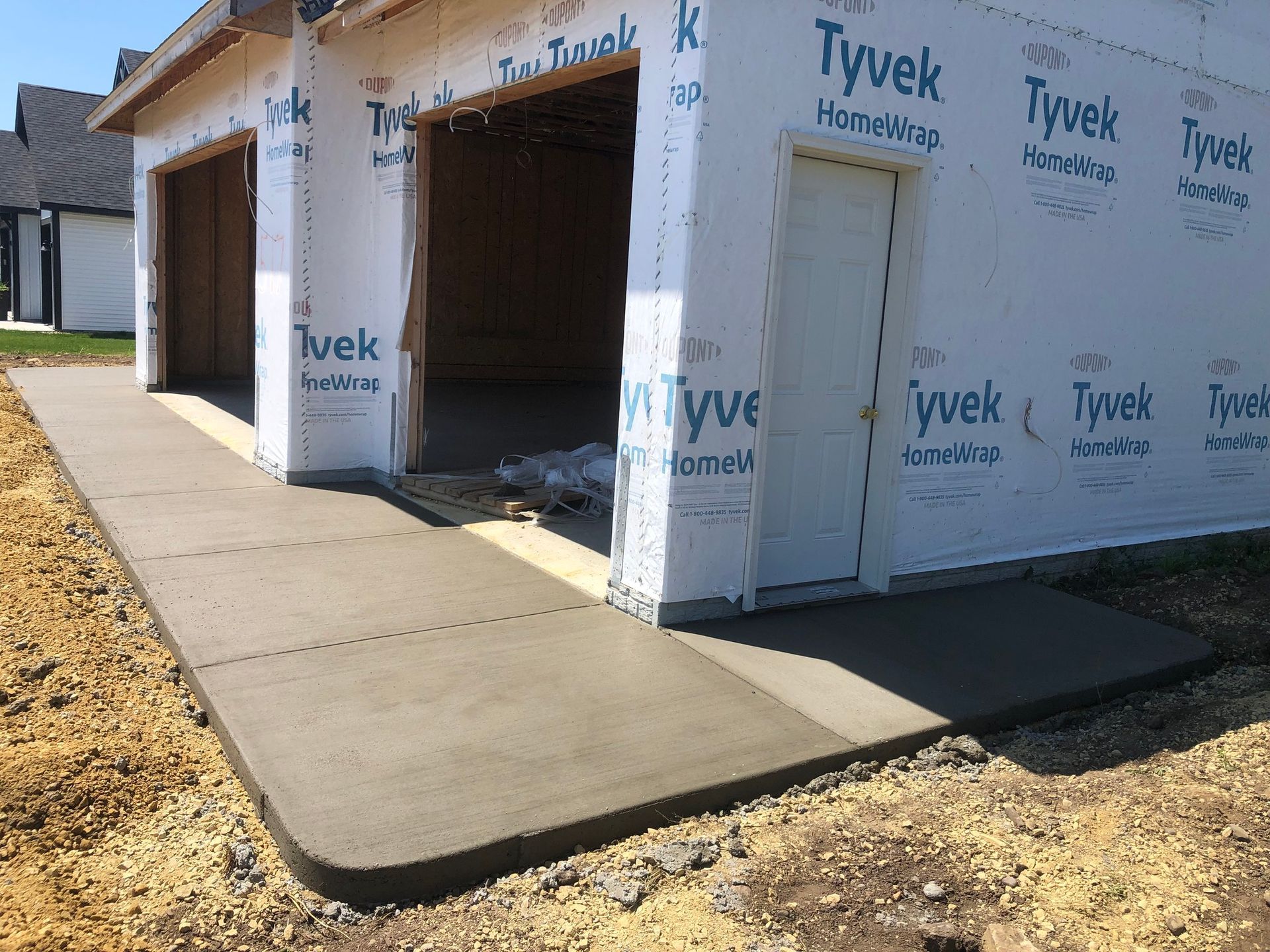 A concrete walkway leading to a garage under construction