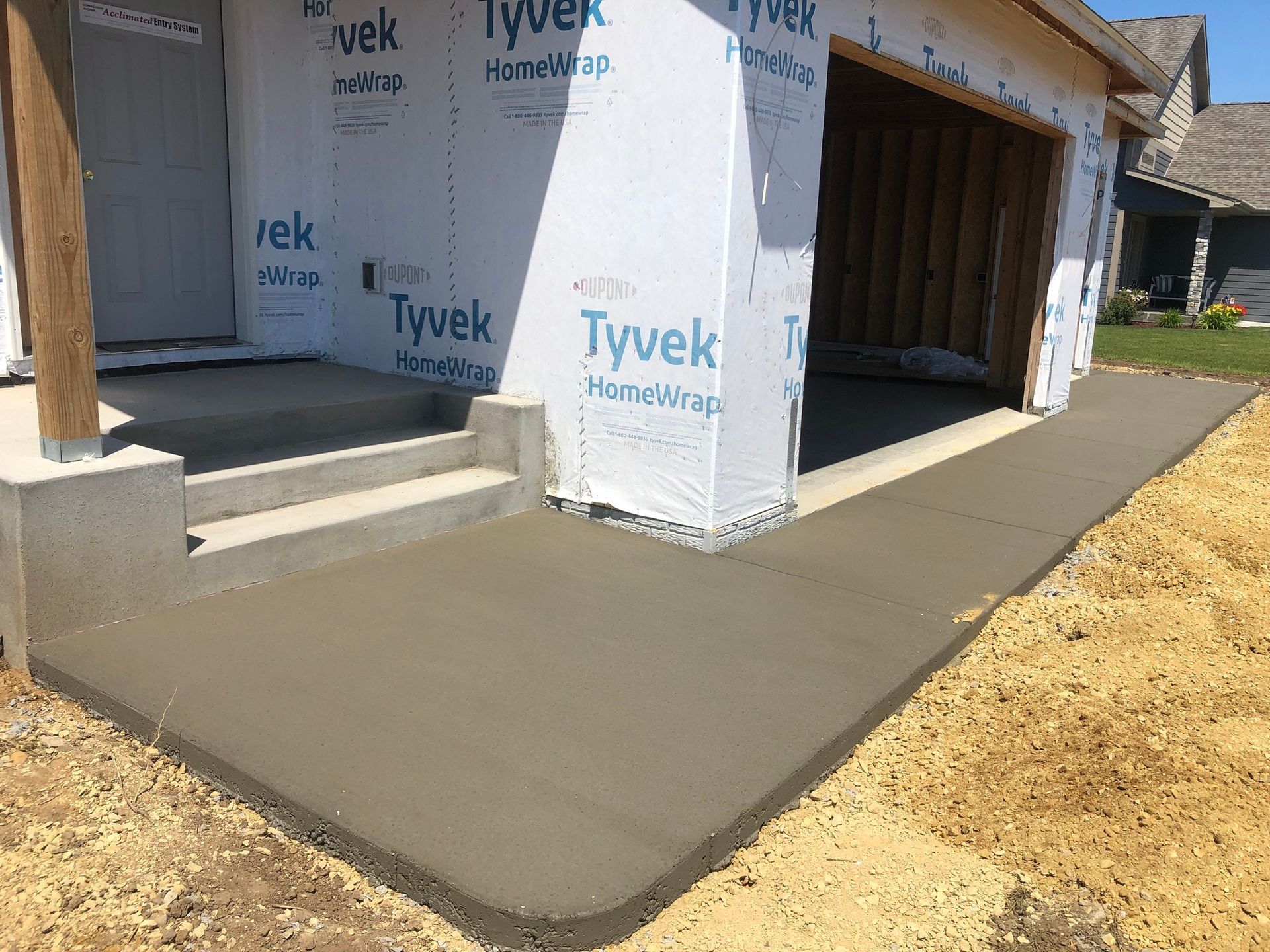 A concrete walkway is being built in front of a garage.