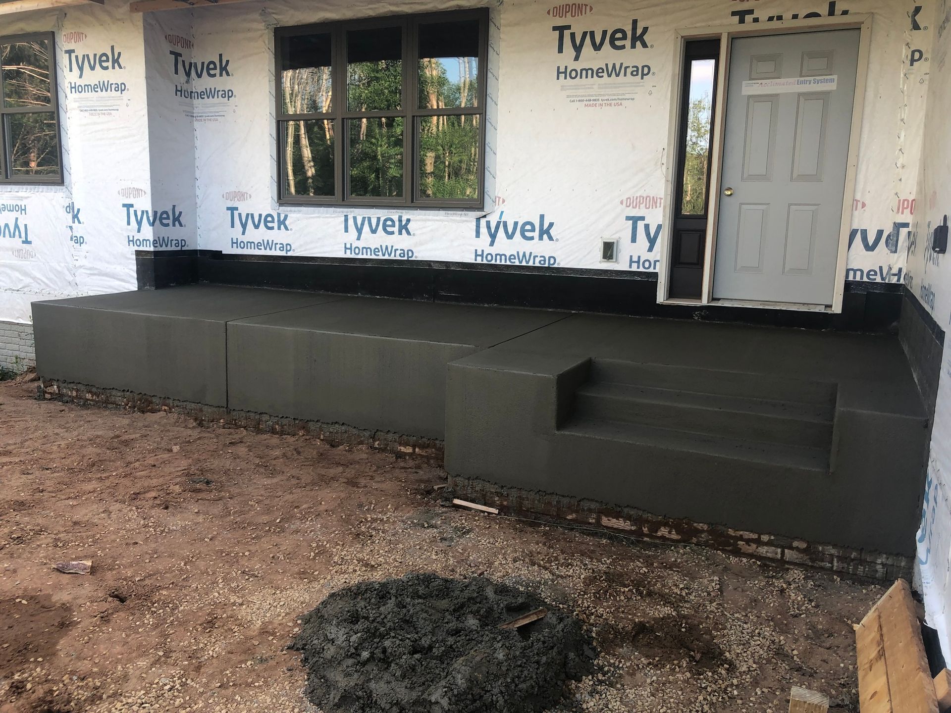 A concrete porch is being built in front of a house.