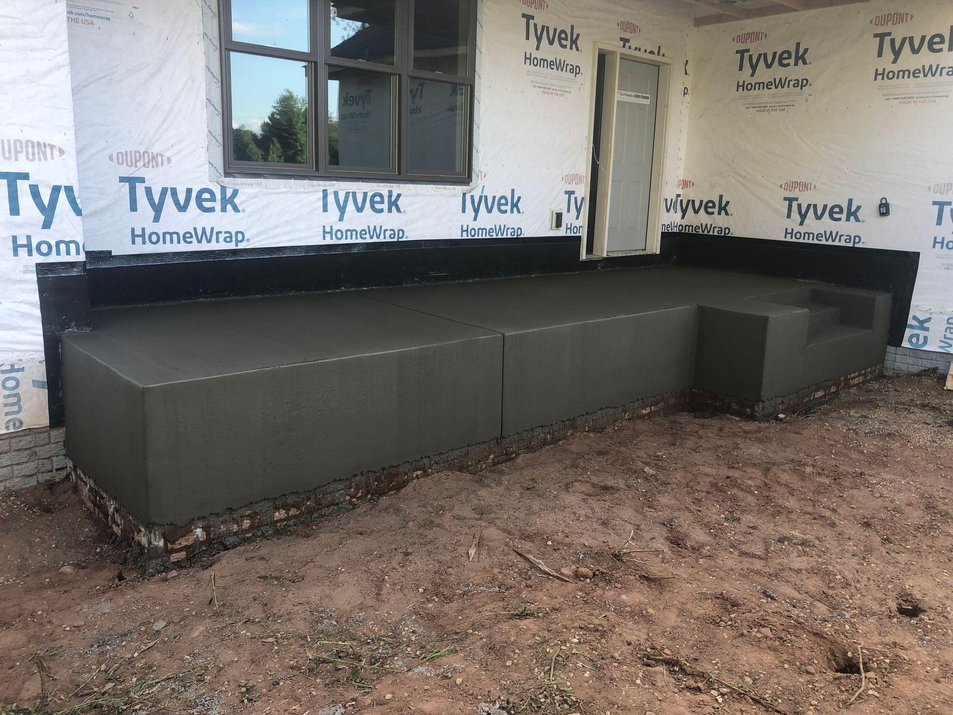A concrete porch is being built in front of a house.