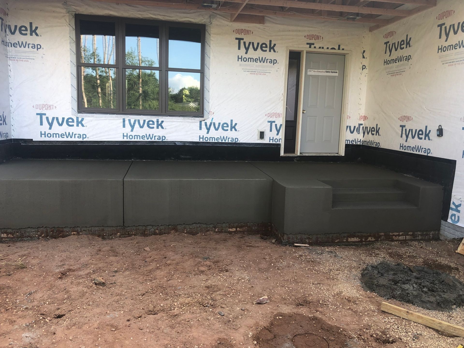 A concrete porch is being built in front of a house.