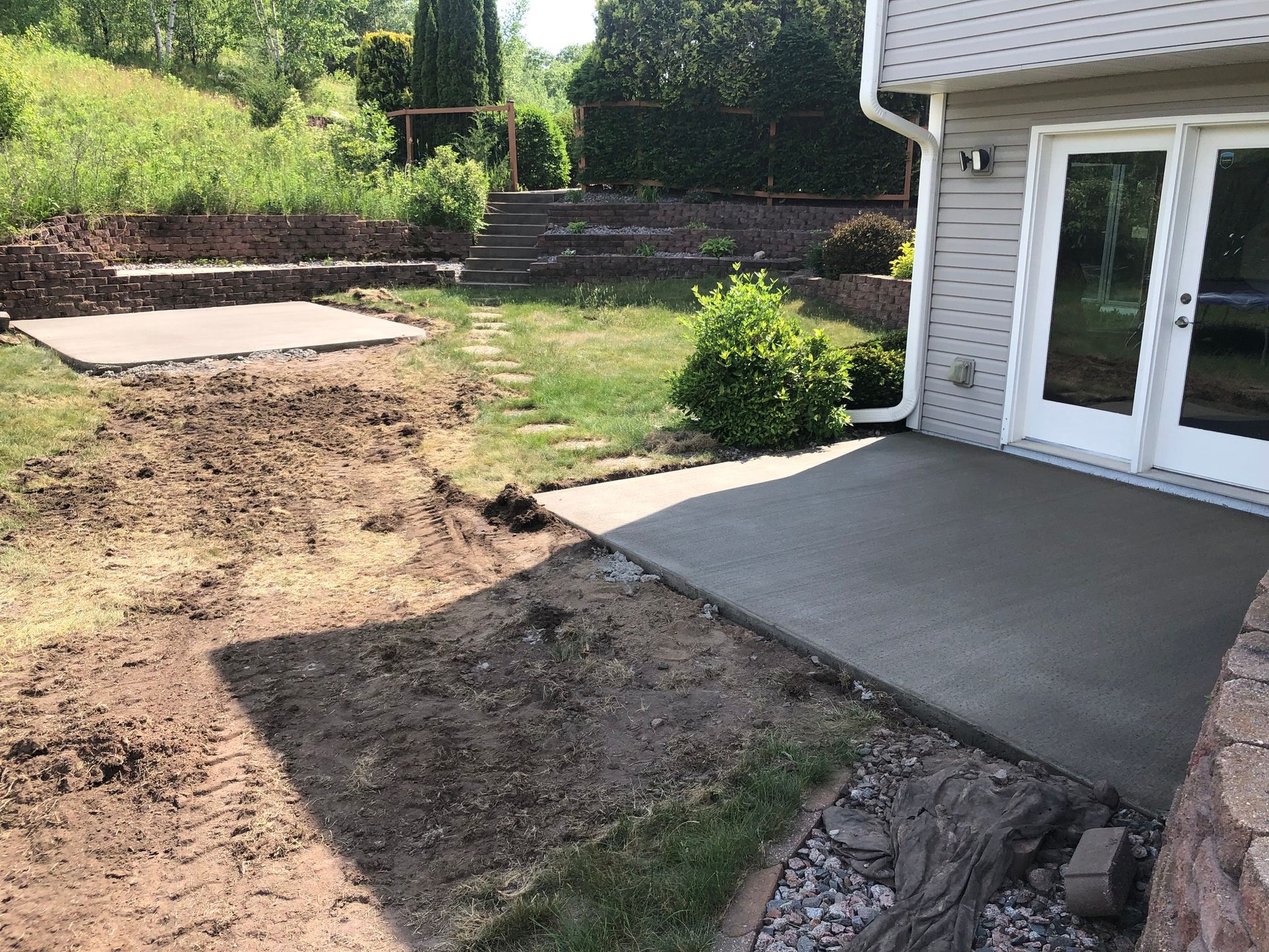 A concrete patio is being built in the backyard of a house.